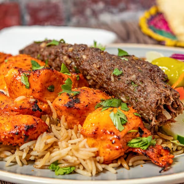Chaska Kabob & Rice's chicken tikka and seekh kabob with rice, garnished with fresh cilantro.