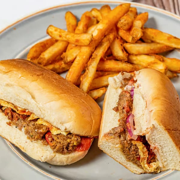 Two Pakistani street food sandwiches with kabob and fries on a gray plate.